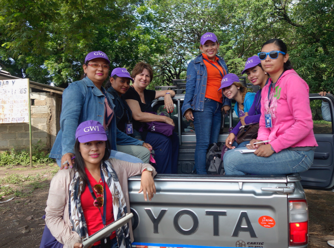 Women in purple hats smiling from a truck